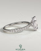 Kynora CJ 2ct pear-shaped diamond solitaire engagement ring with wrap-around hidden halo and pave band.