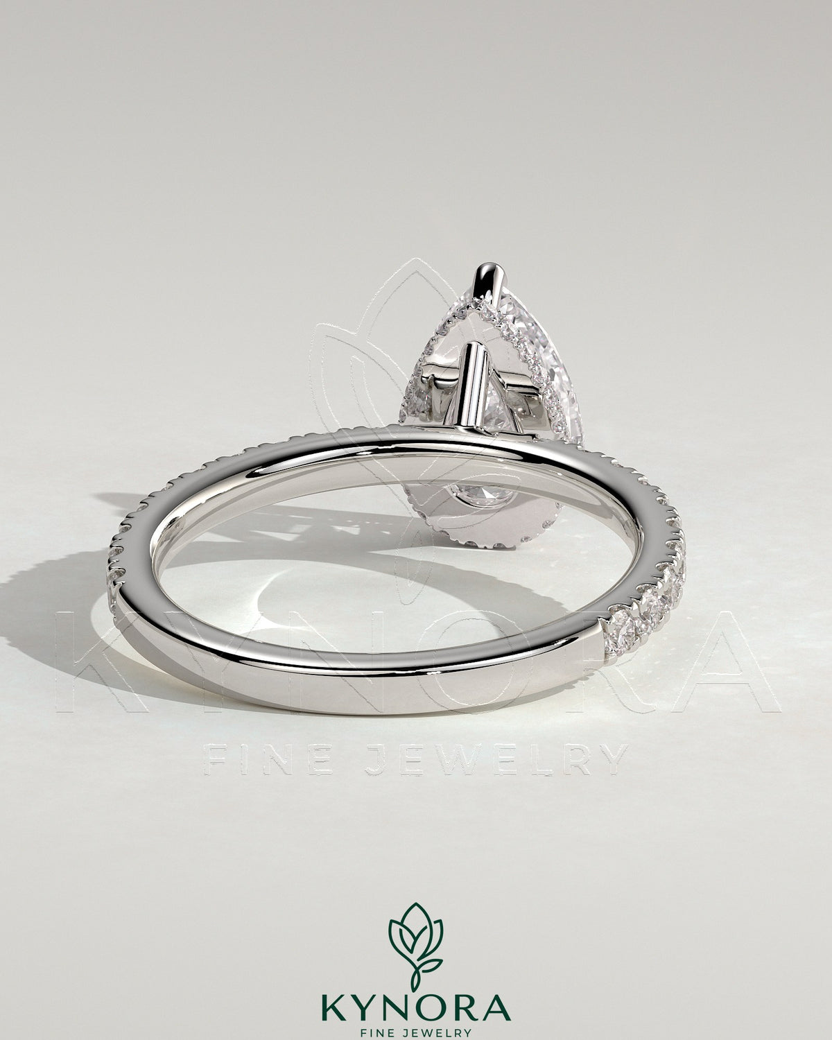 Kynora CJ 2ct pear-shaped diamond solitaire engagement ring with wrap-around hidden halo and pavé band, three-prong setting.