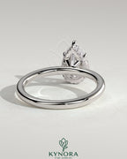 Kynora CJ 2ct pear-shaped diamond solitaire engagement ring with a wrap-around hidden halo design, crafted in elegant jewelry style.
