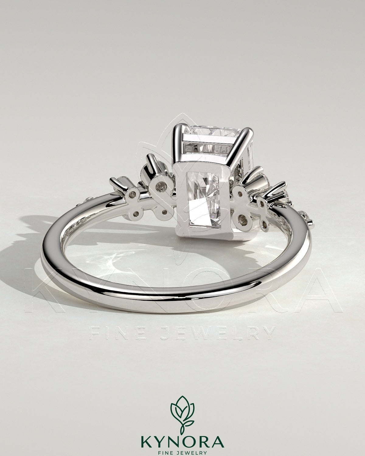 Kynora CJ 2ct radiant claw solitaire engagement ring with clustered round shoulder stones, featuring a sparkling central diamond.