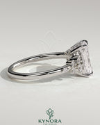 Kynora CJ 2ct radiant claw solitaire engagement ring with clustered round shoulder stones, featuring a polished gold band.