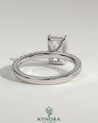 Kynora CJ 2ct radiant claw solitaire engagement ring with hidden halo and pavé band, featuring sparkling diamond accents.