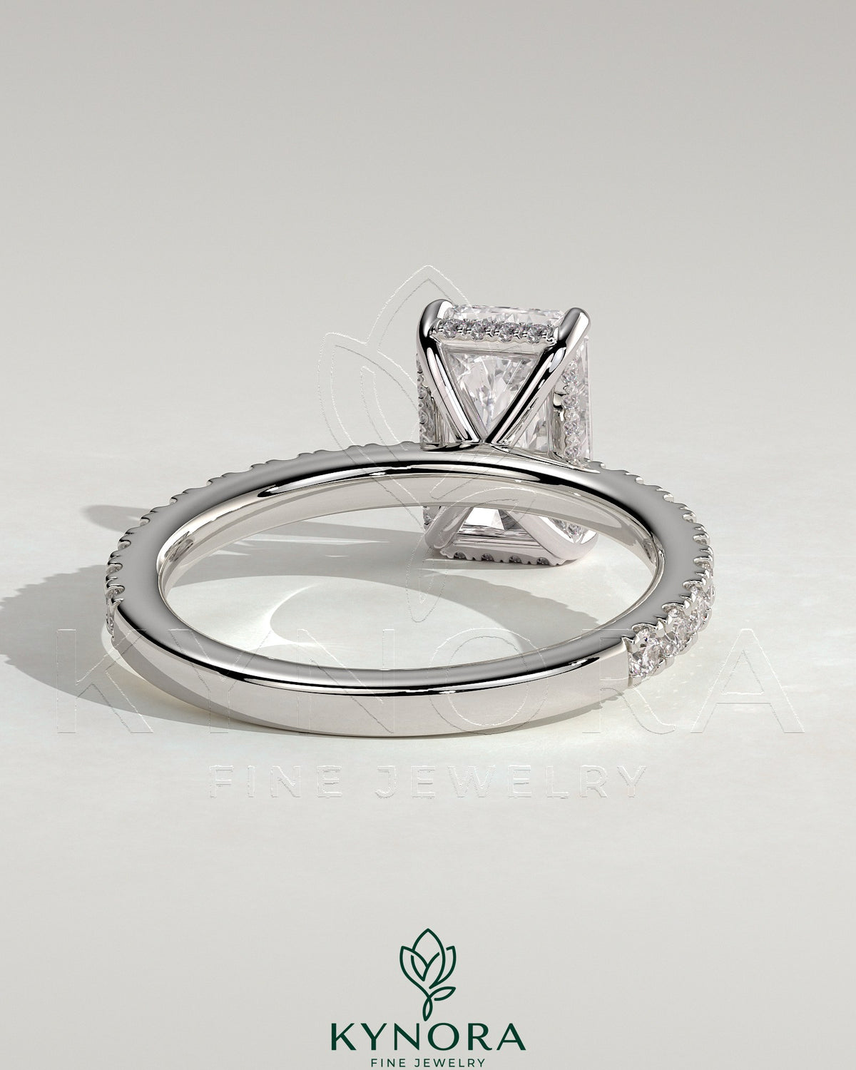 Kynora CJ 2ct radiant claw solitaire engagement ring with hidden halo and pavé band, featuring sparkling diamond accents.