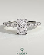Kynora CJ 2ct radiant claw solitaire engagement ring with marquise and round accent stones, featuring a wrap-around hidden halo design.