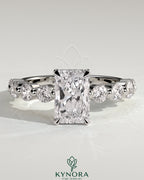 Kynora CJ 2ct radiant claw solitaire engagement ring with round accent stones and hidden halo design.