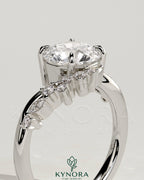 Kynora CJ 2ct round claw solitaire engagement ring with bypass band and cluster of round-marquise accent stones.