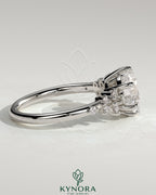 Kynora CJ 2ct round claw solitaire engagement ring with clustered round shoulder stones, elegant and sparkling jewelry piece.