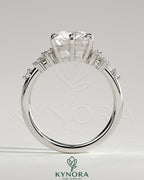 Kynora CJ 2-carat round claw solitaire engagement ring with clustered round shoulder stones, elegant and sparkling jewelry piece.