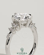 Kynora CJ 2ct round claw solitaire engagement ring with clustered shoulder stones, elegant and sparkling jewelry design.