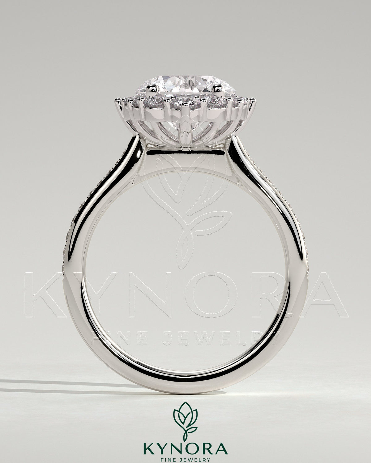 Kynora CJ 2ct round claw solitaire engagement ring with graduating halo, bead set micropave accents, and tapered band.