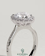 Kynora CJ 2ct round claw solitaire engagement ring with graduating halo, bead-set micropave, and tapered band.