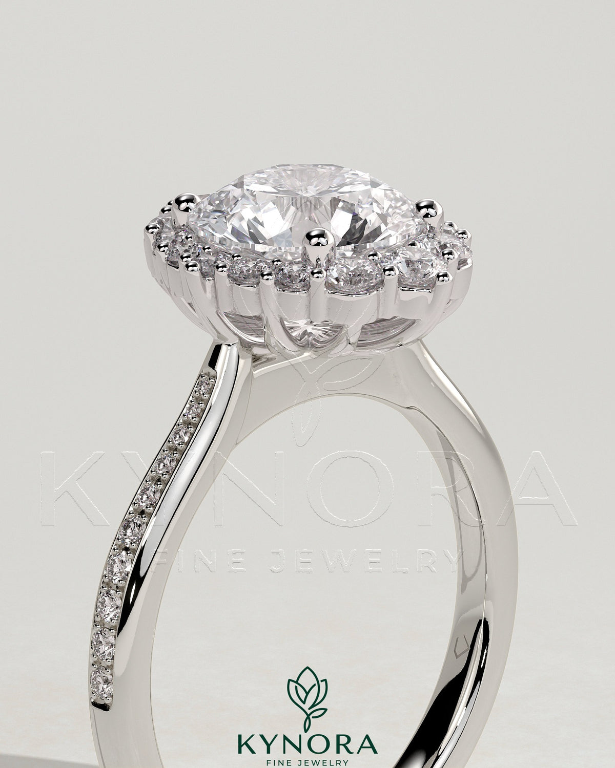 Kynora CJ 2ct round claw solitaire engagement ring with graduating halo, bead-set micropave, and tapered band.