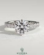 Kynora CJ 2ct round diamond claw solitaire engagement ring with half eternity band, showcasing sparkling center stone and elegant design.