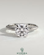 Kynora CJ 2ct round claw solitaire engagement ring with hidden halo and knife edge pave band, elegant diamond ring design