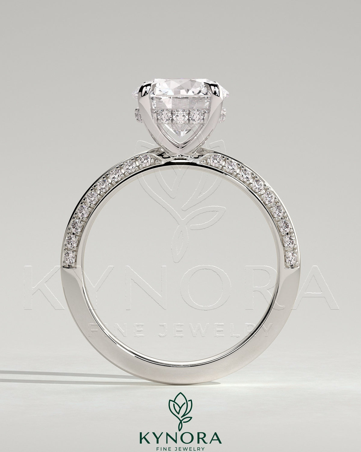 Kynora CJ 2ct round claw solitaire engagement ring with hidden halo and knife edge pave band, featuring sparkling diamond details.