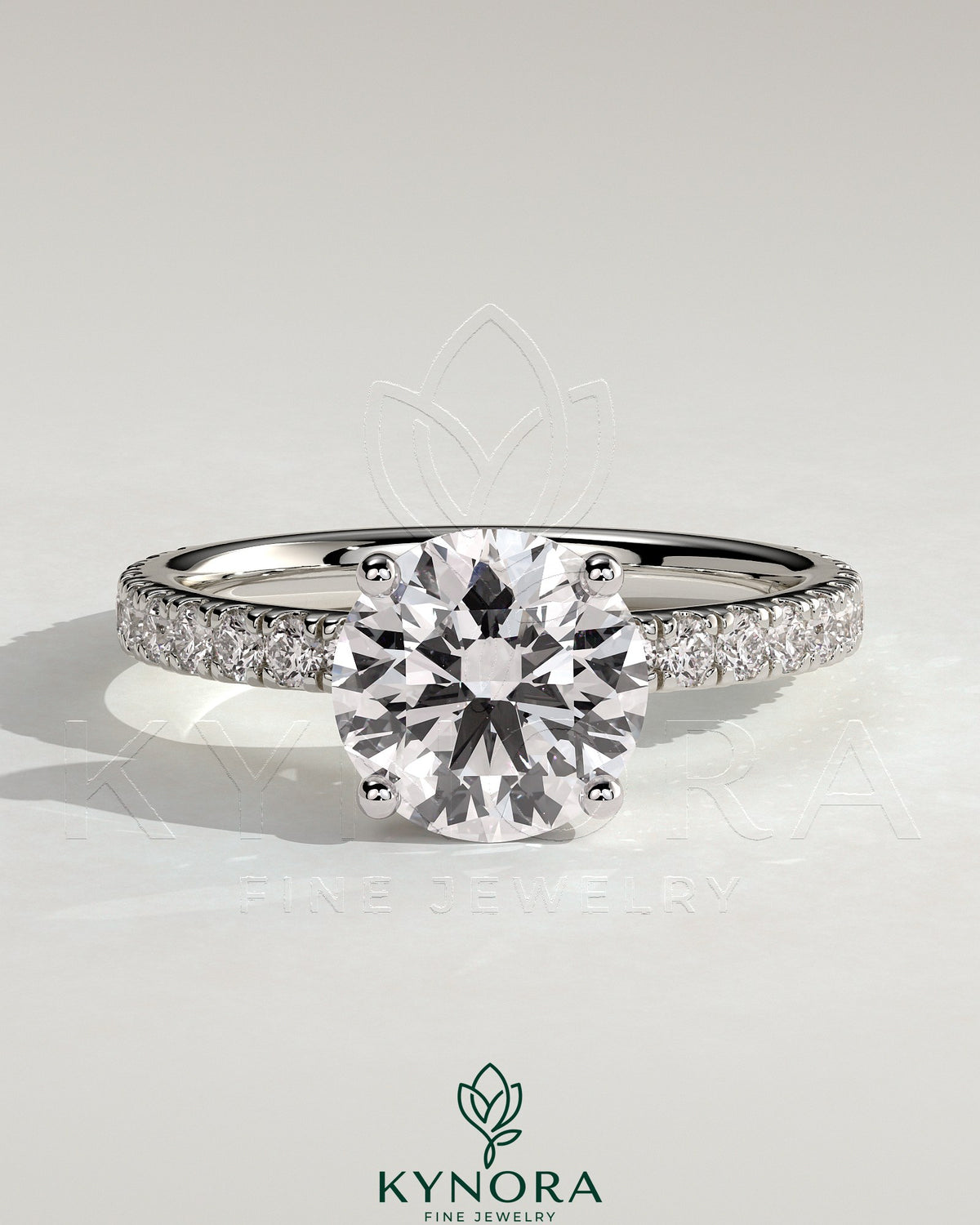 Kynora CJ 2ct round claw solitaire engagement ring with hidden halo and pavé band, featuring sparkling diamond details.