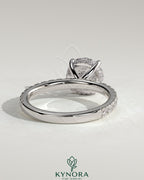 Kynora CJ 2ct round claw solitaire engagement ring with hidden halo and pave band, featuring sparkling diamond accents.