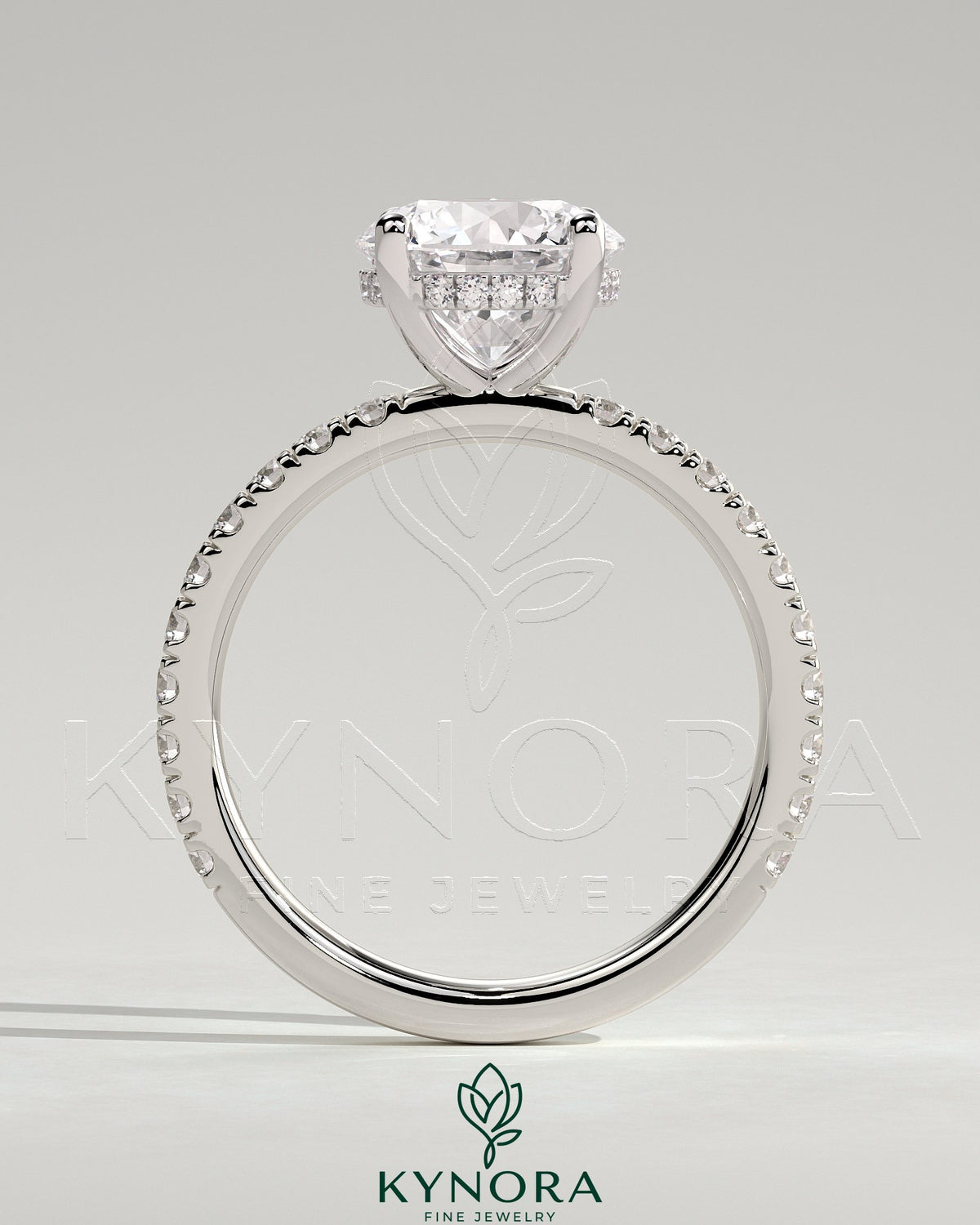 Kynora CJ 2ct round claw solitaire engagement ring with hidden halo and pavé band, showcasing elegant diamond setting and craftsmanship.
