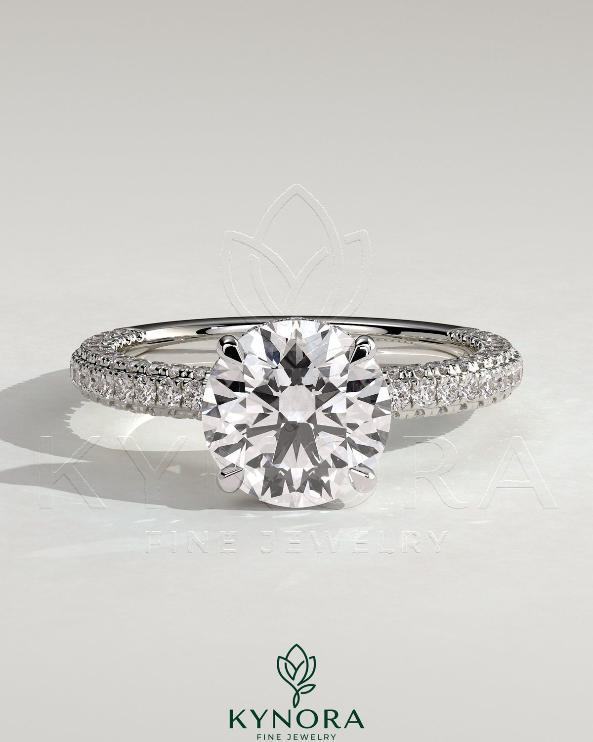 Kynora CJ 2ct round claw solitaire engagement ring with hidden halo and triple pave band, showcasing sparkling diamond details. Main image