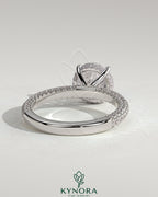 Kynora CJ 2ct round claw solitaire engagement ring with hidden halo and triple pave band, featuring intricate diamond detailing.