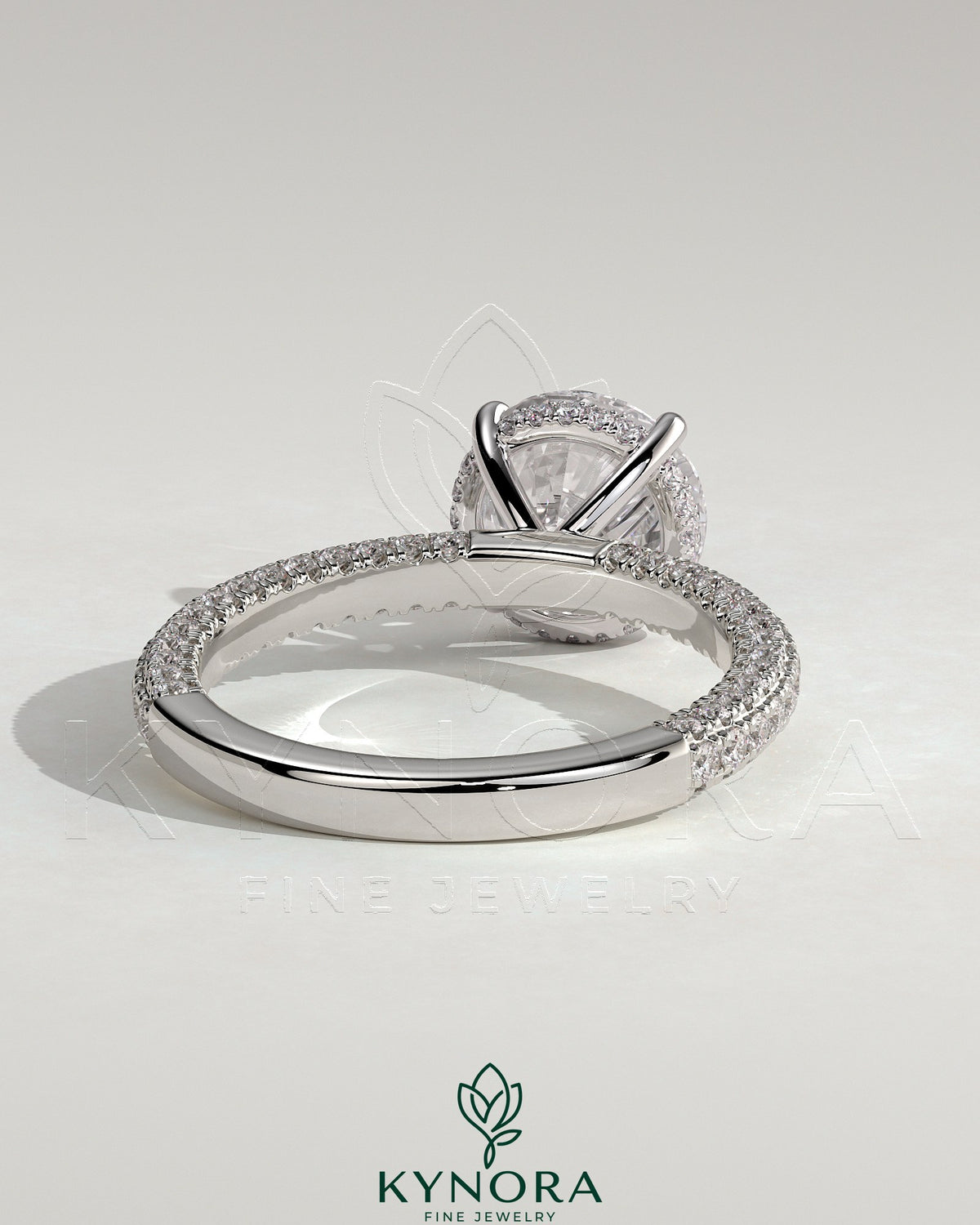 Kynora CJ 2ct round claw solitaire engagement ring with hidden halo and triple pave band, featuring intricate diamond detailing.