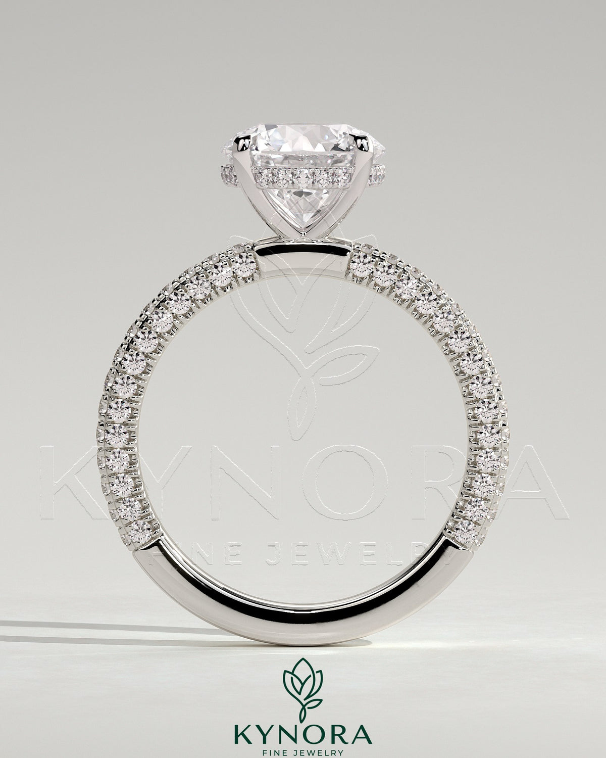 Kynora CJ 2ct round claw solitaire engagement ring with hidden halo and triple pave band, featuring sparkling diamond details.