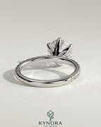 Kynora CJ 2ct round claw solitaire engagement ring with pavé band showcasing a sparkling center diamond and intricate band details.