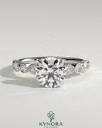 Kynora CJ 2ct round claw solitaire engagement ring with round-marquise bezel accent stones in a sleek design.