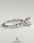 Kynora CJ 2ct round claw solitaire engagement ring with round-marquise bezel accent stones, elegant and sparkling jewelry piece.