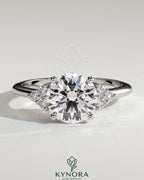Kynora CJ 2ct round claw solitaire engagement ring with round shoulder stones, showcasing elegant diamond setting and band details.