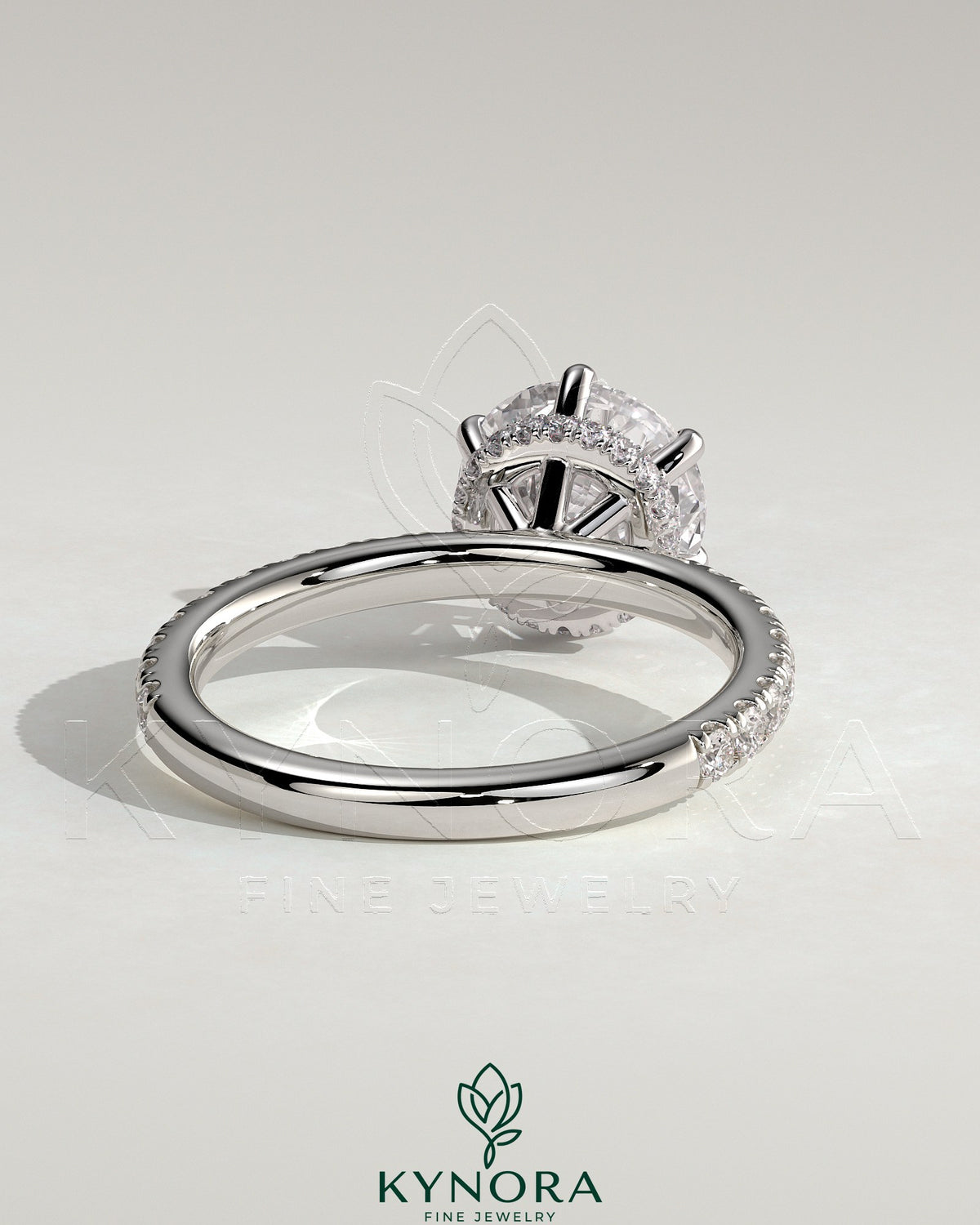 Kynora CJ 2ct round claw solitaire engagement ring with wrap-around hidden halo and pavé band, showcasing elegant jewelry craftsmanship.
