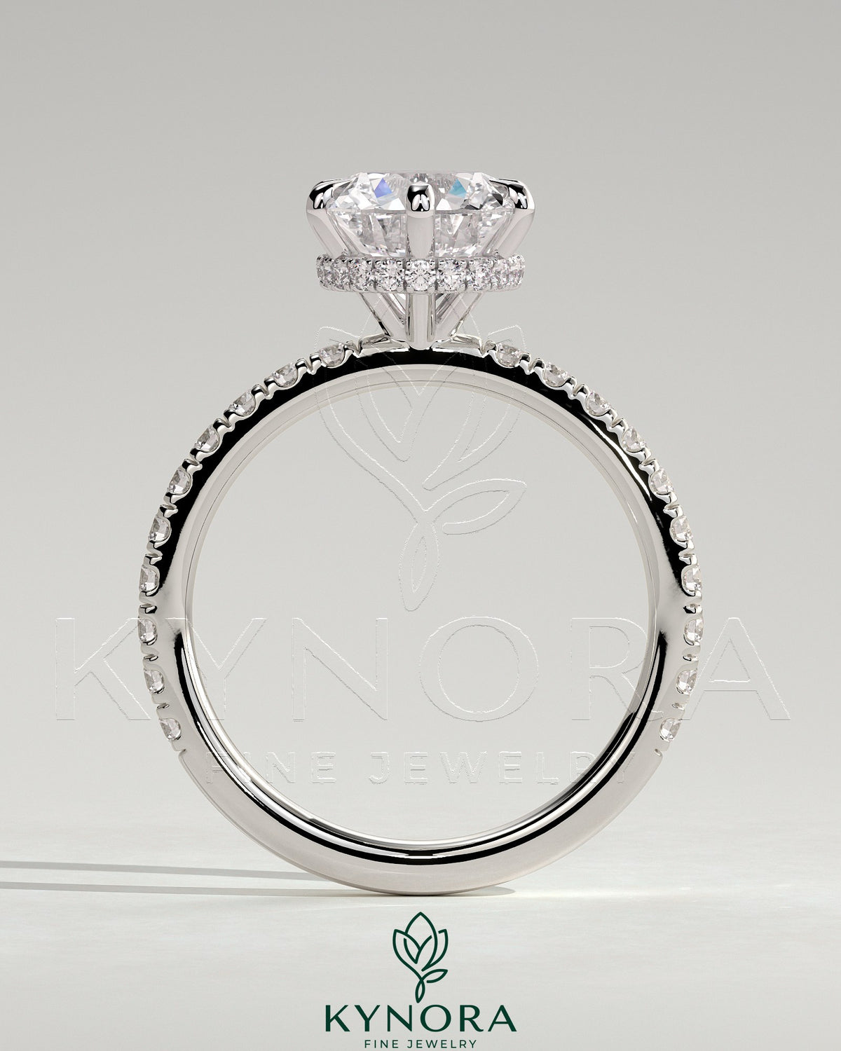 Kynora CJ 2ct round claw solitaire engagement ring with wrap-around hidden halo and pave band, showcasing elegant diamond setting.