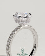 Kynora CJ 2ct round claw solitaire engagement ring with wrap-around hidden halo and pave band, showcasing sparkling diamond details.