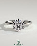 Kynora CJ 2ct round claw solitaire engagement ring with wrap-around hidden halo in polished gold setting.