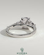 Kynora CJ 2ct elongated cushion claw trilogy engagement ring with pear side stones and pave band, featuring sparkling diamond accents.