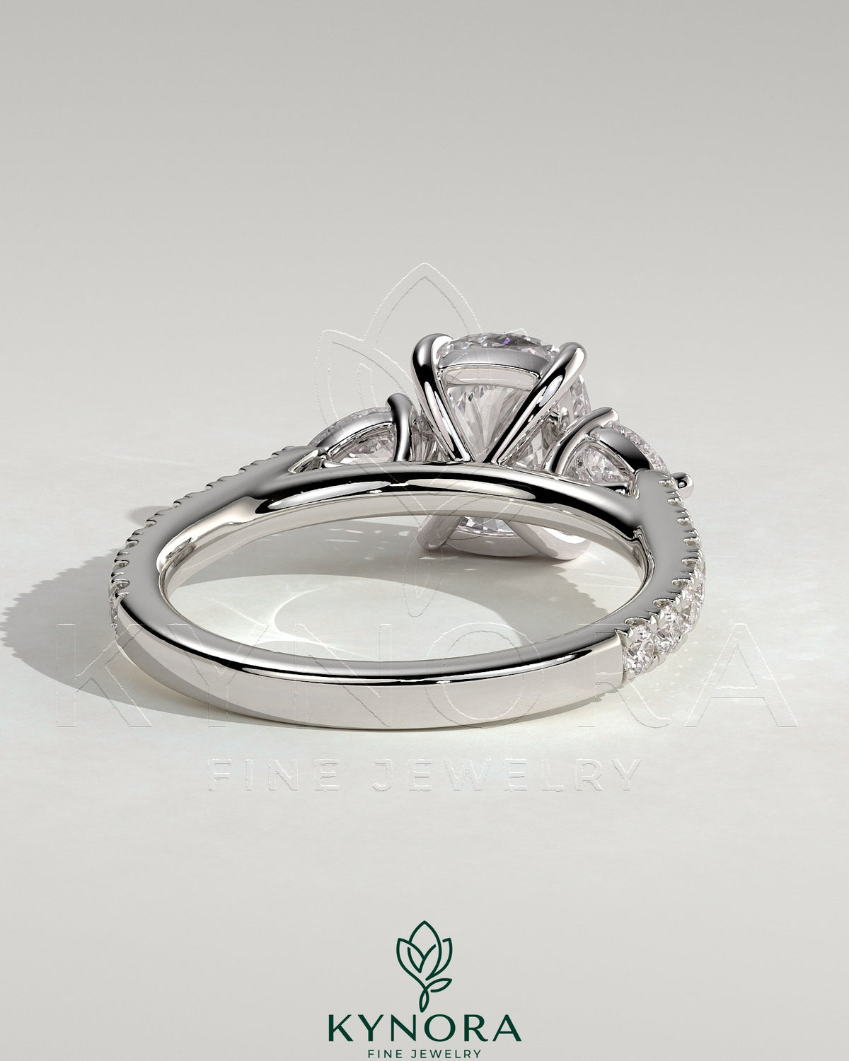 Kynora CJ 2ct elongated cushion claw trilogy engagement ring with pear side stones and pave band, featuring sparkling diamond accents.