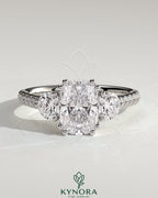 Kynora CJ 2ct elongated three-stone engagement ring with round side stones, pave band, and cathedral setting.