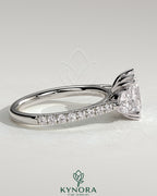 Kynora CJ 2ct elongated cushion double claw trilogy engagement ring with round side stones, pave band, and cathedral setting.
