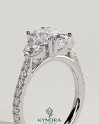 Kynora CJ three stone engagement ring with elongated cushion center stone, round side stones, pave band, cathedral setting.