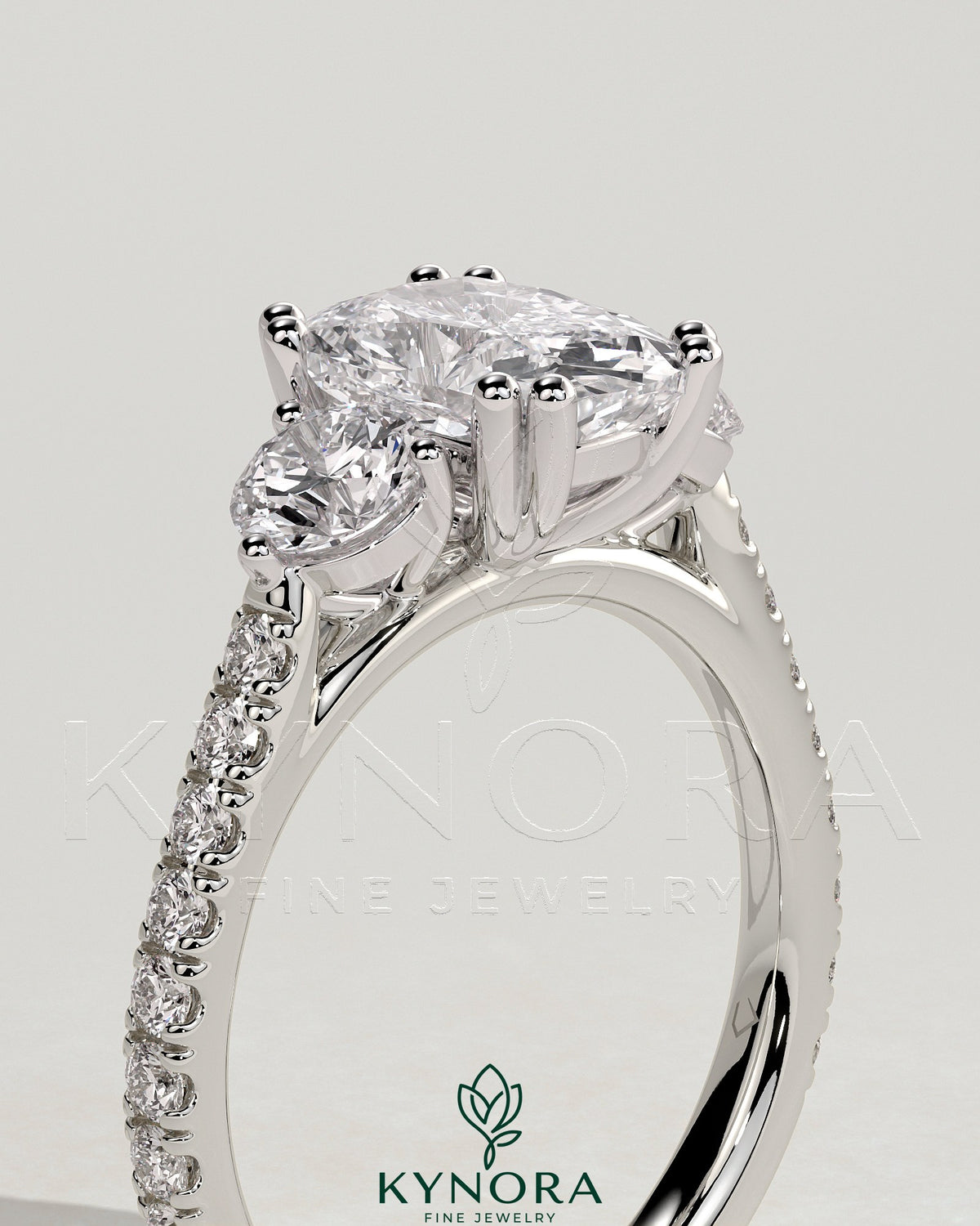 Kynora CJ three stone engagement ring with elongated cushion center stone, round side stones, pave band, cathedral setting.