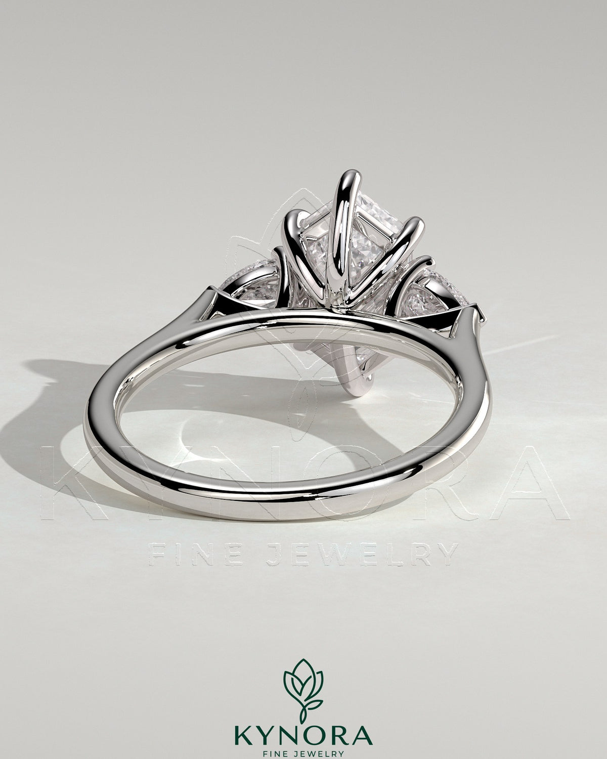 Kynora CJ three-stone engagement ring with 2-carat elongated hexagon diamond, pear side stones, cathedral setting, elegant jewelry.