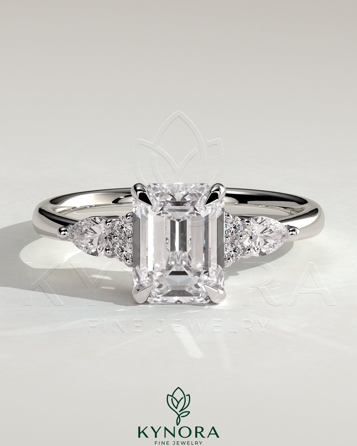 Kynora CJ 2ct emerald claw solitaire engagement ring with pear-shaped accents and round shoulder stones, three stone design. Main image