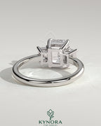 Kynora CJ 2ct emerald claw trilogy engagement ring with emerald side stones and low setting, showcasing fine craftsmanship.