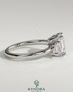 Three-stone emerald engagement ring by Kynora CJ featuring a 2ct center emerald with side stones and a low setting.
