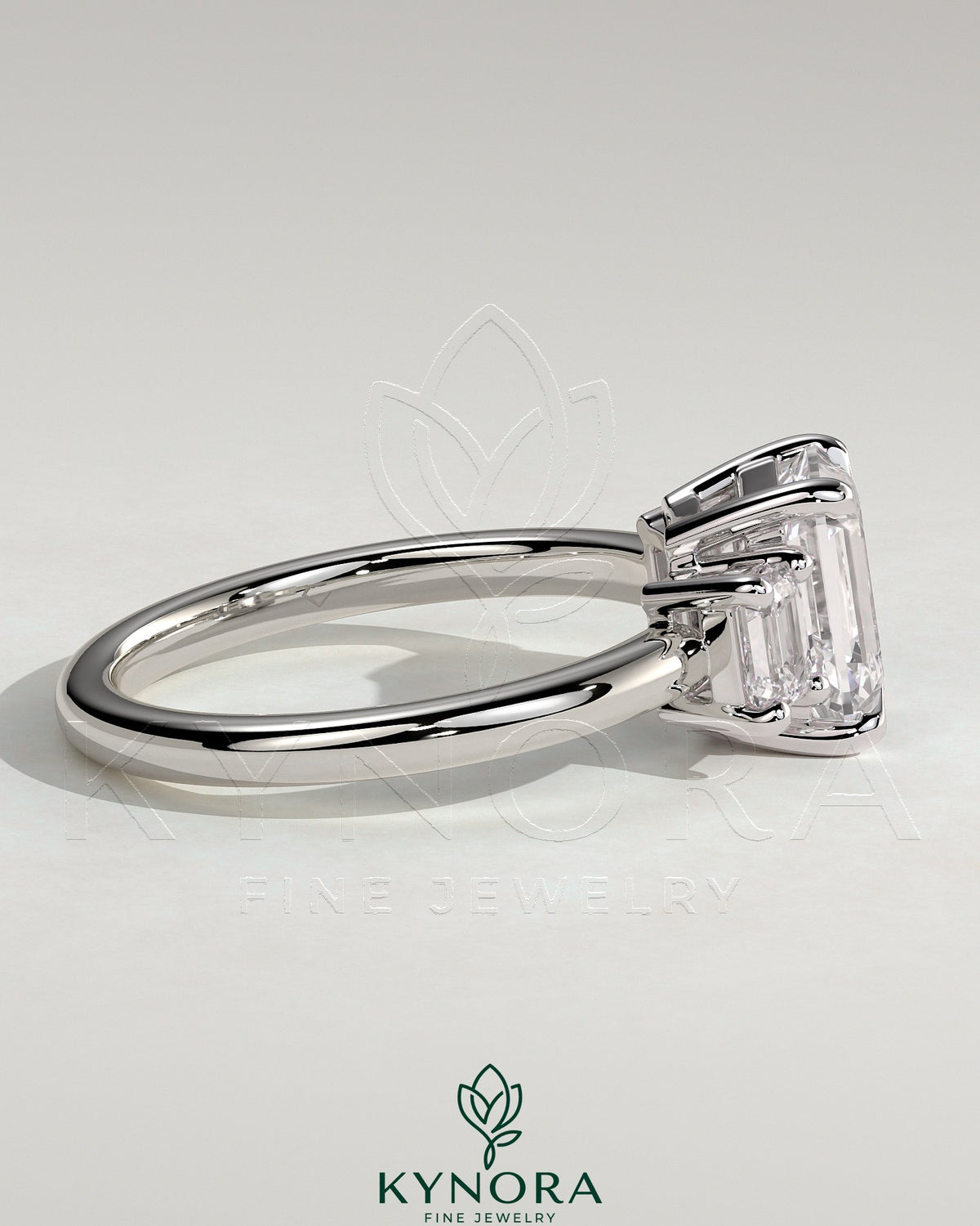 Three-stone emerald engagement ring by Kynora CJ featuring a 2ct center emerald with side stones and a low setting.