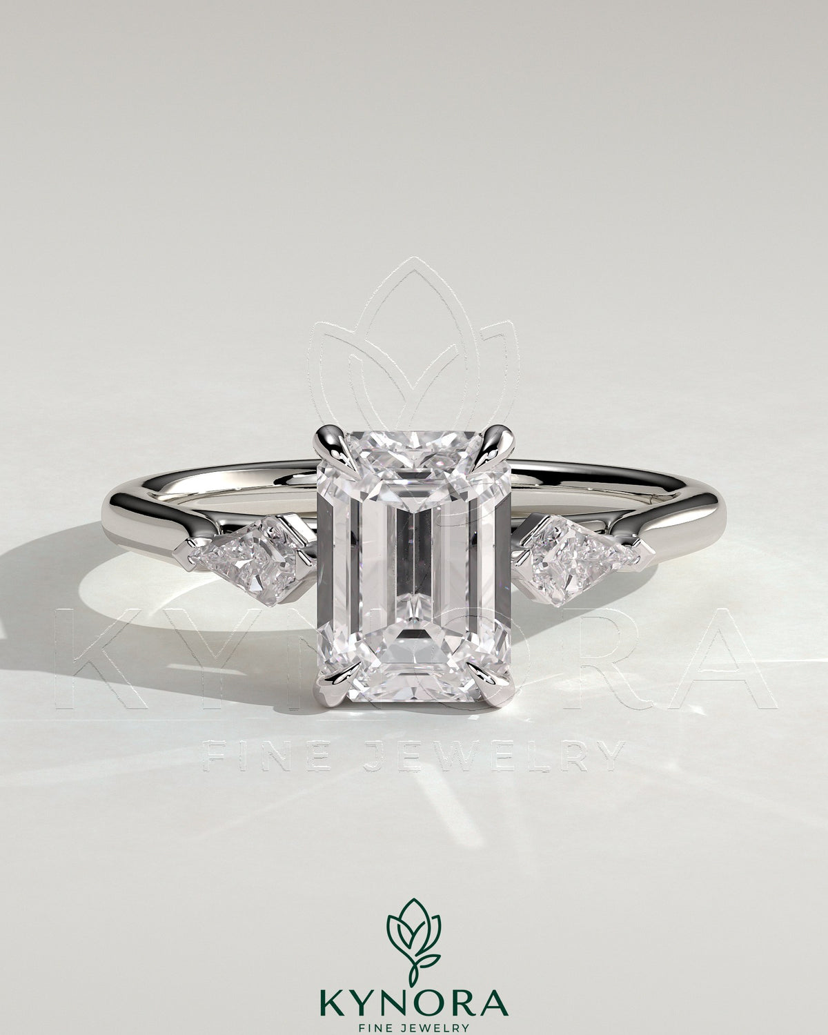 Kynora CJ 2ct emerald claw trilogy engagement ring with kite side stones, featuring a three stone design and detailed craftsmanship.