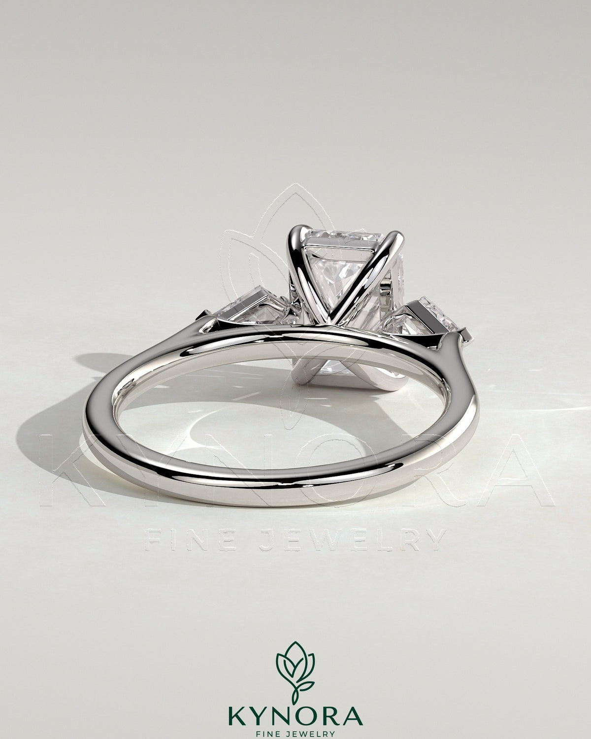 Kynora CJ 2ct emerald claw trilogy engagement ring with kite side stones, featuring a three-stone design and intricate detailing.