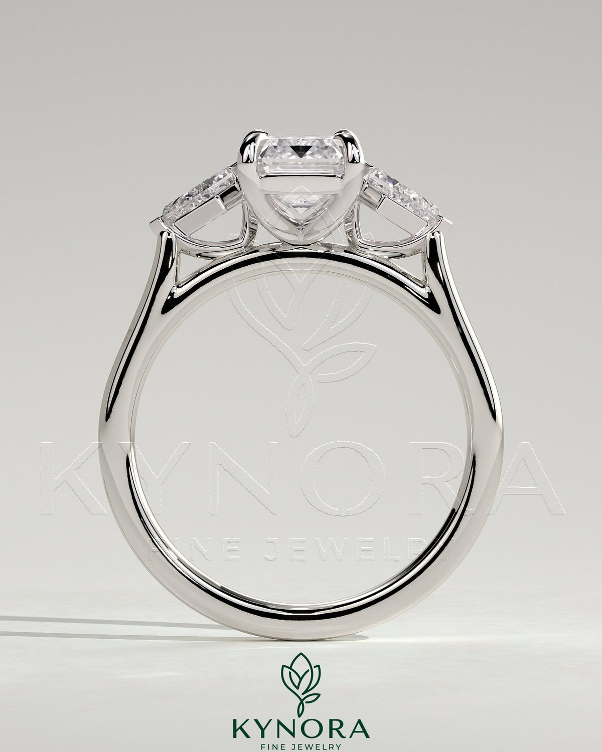 Kynora CJ 2ct emerald claw trilogy engagement ring with kite side stones, featuring a three-stone design and sparkling accents.