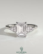 Kynora CJ 2ct emerald claw trilogy engagement ring with pear side stones and cathedral setting in yellow gold.