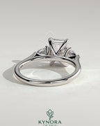 Kynora CJ 2ct emerald claw trilogy engagement ring with pear side stones and cathedral setting, showcasing intricate design and sparkling gemstones.